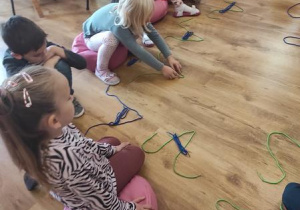 Dzieci układają kształt wielkiej i małej litery A ze sznurka.